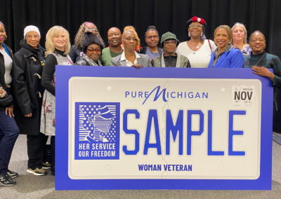 Image of Women Veterans in a group with a Michigan Women Veterans License Plate for a Vehicle.
